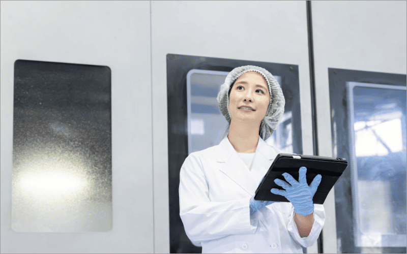 白衣でタブレット端末を持つ女性